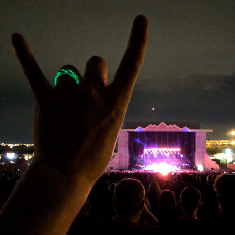 Carbon Fiber Glow Ring Glowing While Worn On A Finger At A Concert