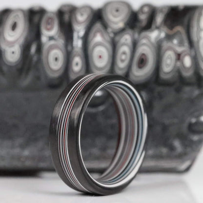 Fordite Men's Ring with Carbon Fiber Rails On Fordite Backdrop