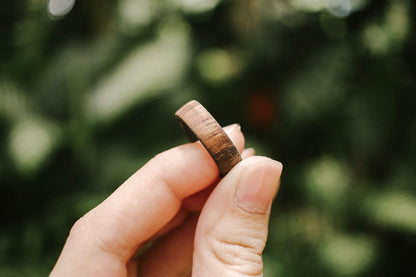 koa wood ring with carbon fiber sleeve held in fingers