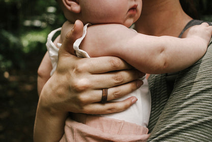 koa wood ring with carbon fiber sleeve worn while holding a baby