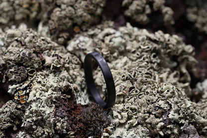 black stackable ring made from carbon fiber in moss