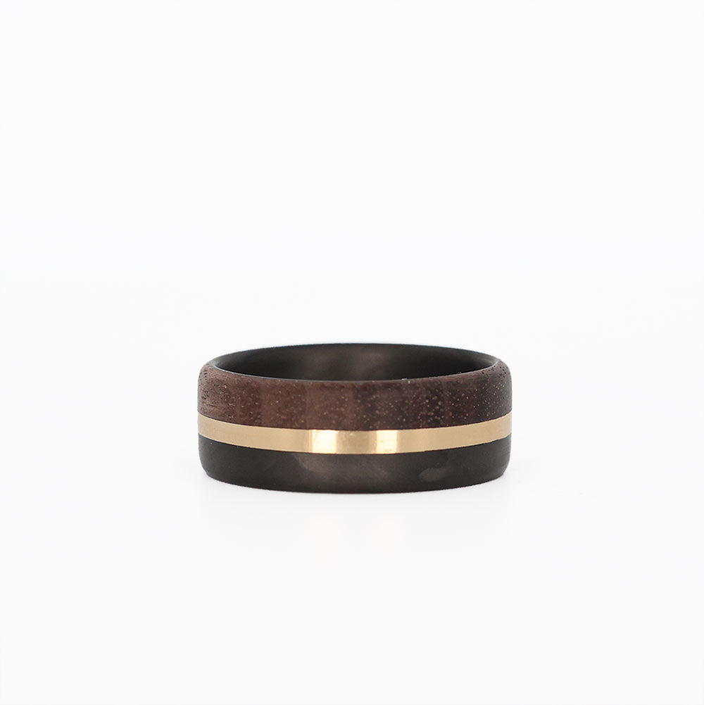 walnut wood and 14 karat yellow gold wedding ring with carbon fiber sleeve laying flat